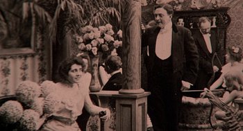 Movie still from “The Blue Lagoon” (1980), directed by Randal Kleiser – An old photo of a man and a woman in formal wear; Medium shot, Low angle