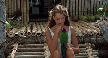 Movie still from “The Blue Lagoon” (1980), directed by Randal Kleiser – A woman holding a green bird in her hands; Medium shot, High angle