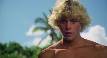 Movie still from “The Blue Lagoon” (1980), directed by Randal Kleiser – A young man with blonde hair is posing for a picture; Close Up shot, Low angle