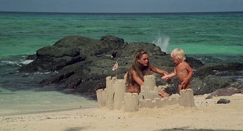 Movie still from “The Blue Lagoon” (1980), directed by Randal Kleiser – A woman and a child are playing in the sand on the beach; Wide shot, High angle