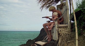 Movie still from “The Blue Lagoon” (1980), directed by Randal Kleiser – A man and a child sitting on a cliff by the ocean; Wide shot, High angle