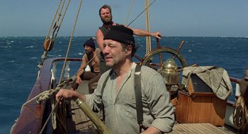 Movie still from “The Blue Lagoon” (1980), directed by Randal Kleiser – A man on a boat in the ocean with two other men on the deck; Medium shot, Low angle