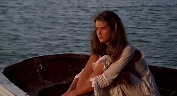 Movie still from “The Blue Lagoon” (1980), directed by Randal Kleiser – A woman sitting in a boat on a body of water; Medium shot, High angle
