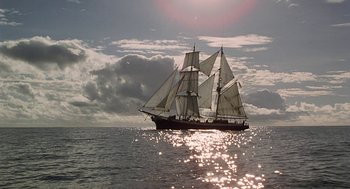 Movie still from “The Blue Lagoon” (1980), directed by Randal Kleiser – A large sail boat sailing on the water; Extreme Wide shot, Low angle