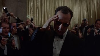 Movie still from “The Bonfire of the Vanities” (1990), directed by Brian De Palma – A man saluting in front of a crowd of onlookers; Medium shot, Low angle