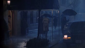 Movie still from “The Bonfire of the Vanities” (1990), directed by Brian De Palma – A group of people under an umbrella on a rainy night; Wide shot, High angle