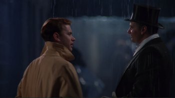 Movie still from “The Bonfire of the Vanities” (1990), directed by Brian De Palma – Two men are standing in the rain talking to each other; Medium shot, Over the shoulder angle