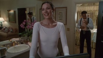 Movie still from “The Bonfire of the Vanities” (1990), directed by Brian De Palma – A woman standing in front of a bathroom mirror; Medium shot, Over the shoulder angle