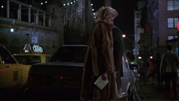 Movie still from “The Bonfire of the Vanities” (1990), directed by Brian De Palma – A woman standing next to a car on a street; Wide shot, Over the shoulder angle