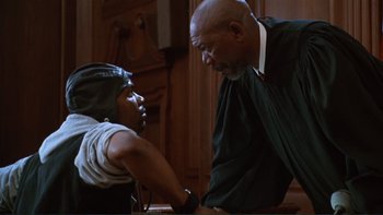 Movie still from “The Bonfire of the Vanities” (1990), directed by Brian De Palma – A man and a woman are talking in a courtroom; Medium shot, Low angle