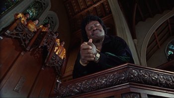 Movie still from “The Bonfire of the Vanities” (1990), directed by Brian De Palma – A man is praying in a large church; Medium shot, Low angle