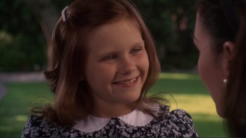 Movie still from “The Bonfire of the Vanities” (1990), directed by Brian De Palma – A little girl with long brown hair smiles for the camera; Close Up shot, High angle