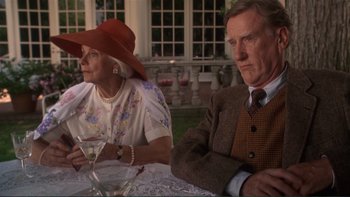 Movie still from “The Bonfire of the Vanities” (1990), directed by Brian De Palma – An older man and woman sitting at a dinner table; Medium shot, Low angle