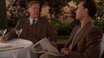 Movie still from “The Bonfire of the Vanities” (1990), directed by Brian De Palma – Two men are sitting at a table and one is reading a newspaper; Medium shot, Over the shoulder angle