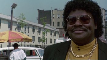 Movie still from “The Bonfire of the Vanities” (1990), directed by Brian De Palma – A man in sunglasses and a jacket standing on the side of the street; Close Up shot, Low angle