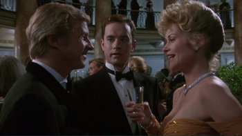 Movie still from “The Bonfire of the Vanities” (1990), directed by Brian De Palma – Two men and a woman in formal wear at a party; Medium shot, Over the shoulder angle