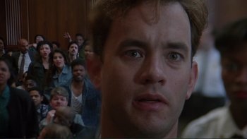 Movie still from “The Bonfire of the Vanities” (1990), directed by Brian De Palma – A man's face in front of a group of people; Close Up shot, Low angle