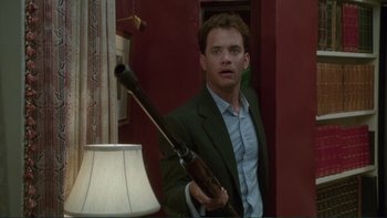 Movie still from “The Bonfire of the Vanities” (1990), directed by Brian De Palma – A man in a suit holding a rifle in a room; Medium shot, Low angle