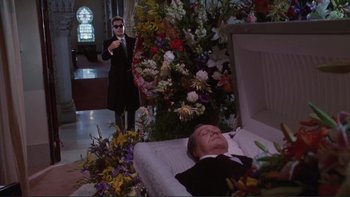 Movie still from “The Bonfire of the Vanities” (1990), directed by Brian De Palma – A man in a suit and tie standing next to a corpse; Wide shot, Low angle