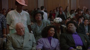 Movie still from “The Bonfire of the Vanities” (1990), directed by Brian De Palma – A group of people sitting together in a room; Medium shot, High angle