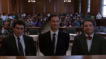 Movie still from “The Bonfire of the Vanities” (1990), directed by Brian De Palma – A man in a suit sitting in front of an audience; Medium shot, Low angle