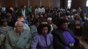 Movie still from “The Bonfire of the Vanities” (1990), directed by Brian De Palma – A group of people sitting in a room; Medium shot, High angle