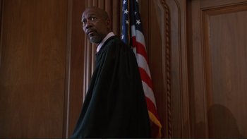 Movie still from “The Bonfire of the Vanities” (1990), directed by Brian De Palma – A man in a robe stands in front of an american flag; Medium shot, Low angle