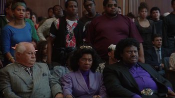 Movie still from “The Bonfire of the Vanities” (1990), directed by Brian De Palma – A group of people sitting in a room together; Medium shot, High angle