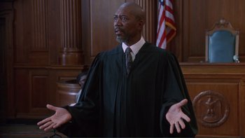 Movie still from “The Bonfire of the Vanities” (1990), directed by Brian De Palma – A man in a robe and tie in front of a judge; Medium shot, Low angle