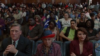 Movie still from “The Bonfire of the Vanities” (1990), directed by Brian De Palma – A group of people sitting in a room watching a movie; Medium shot, High angle