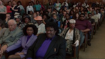 Movie still from “The Bonfire of the Vanities” (1990), directed by Brian De Palma – A large group of people sitting in a room; Medium shot, High angle