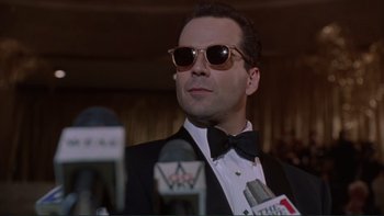 Movie still from “The Bonfire of the Vanities” (1990), directed by Brian De Palma – A man in a suit and tie wearing sunglasses and holding a microphone; Close Up shot, Low angle