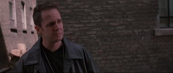 Movie still from “The Boondock Saints” (1999), directed by Troy Duffy – A man wearing a leather jacket standing in front of a brick wall; Close Up shot, Over the shoulder angle