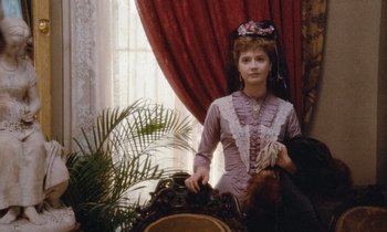 Movie still from “The Bostonians” (1984), directed by James Ivory – A woman standing in front of a mirror in front of a window; Medium shot, High angle
