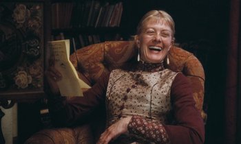 Movie still from “The Bostonians” (1984), directed by James Ivory – An older woman sitting in a chair holding a piece of paper; Medium shot, Low angle