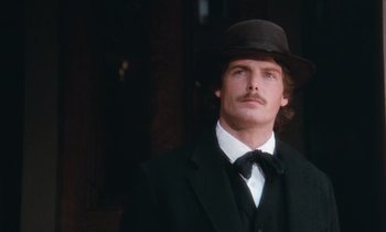 Movie still from “The Bostonians” (1984), directed by James Ivory – A man in a suit and hat standing in front of a building; Close Up shot, Low angle