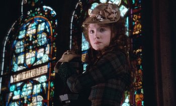 Movie still from “The Bostonians” (1984), directed by James Ivory – A young girl in a plaid shirt and a hat in front of a stained glass window; Close Up shot, Low angle
