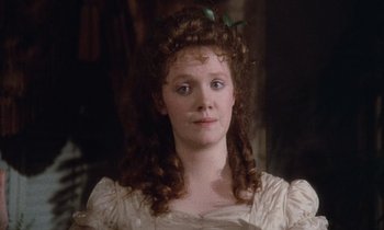 Movie still from “The Bostonians” (1984), directed by James Ivory – A woman with long red curly hair wearing a white dress; Close Up shot, High angle