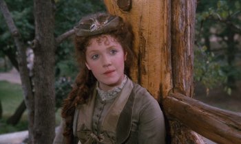Movie still from “The Bostonians” (1984), directed by James Ivory – A young woman wearing a hat standing in front of a tree; Close Up shot, Over the shoulder angle
