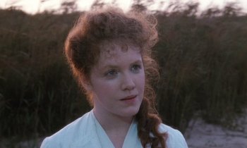 Movie still from “The Bostonians” (1984), directed by James Ivory – A young woman with long red hair wearing a white shirt; Close Up shot, Over the shoulder angle