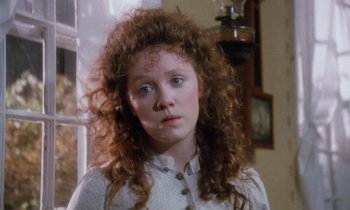 Movie still from “The Bostonians” (1984), directed by James Ivory – A young girl with long curly red hair and blue eyes; Close Up shot, High angle