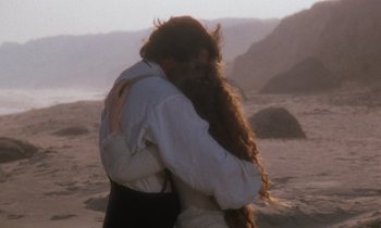 Movie still from “The Bostonians” (1984), directed by James Ivory – A man and a woman hugging on the beach; Medium shot, Over the shoulder angle