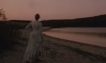 Movie still from “The Bostonians” (1984), directed by James Ivory – A woman in a white dress standing on the beach; Wide shot, Over the shoulder angle