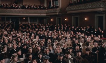 Movie still from “The Bostonians” (1984), directed by James Ivory – A large group of people sitting in front of an audience; Extreme Wide shot, High angle