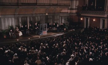 Movie still from “The Bostonians” (1984), directed by James Ivory – A large crowd of people sitting in front of an audience; Extreme Wide shot, High angle