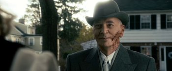 Movie still from “The Box” (2009), directed by Richard Kelly – An older man in a suit and a hat; Close Up shot, Over the shoulder angle