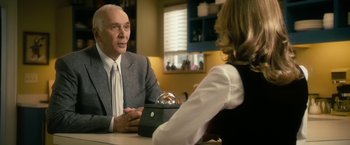 Movie still from “The Box” (2009), directed by Richard Kelly – An older man in a suit and tie sitting at a table with an older woman; Medium shot, Over the shoulder angle