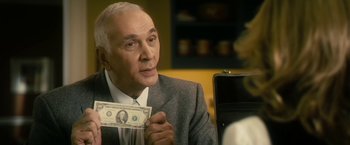 Movie still from “The Box” (2009), directed by Richard Kelly – An older man holding a $ 1 0 0 dollar bill in his hand; Close Up shot, Over the shoulder angle