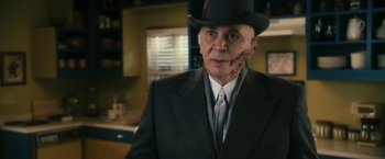 Movie still from “The Box” (2009), directed by Richard Kelly – An older man in a suit and a hat; Close Up shot, Over the shoulder angle