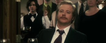 Movie still from “The Box” (2009), directed by Richard Kelly – A man in a suit and tie with a mustache; Close Up shot, Over the shoulder angle